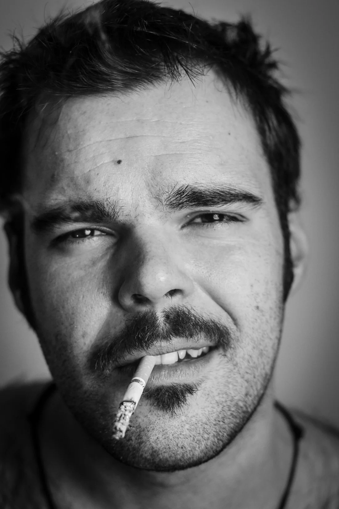 Black-and-white portrait of a man with a cigarette in his mouth